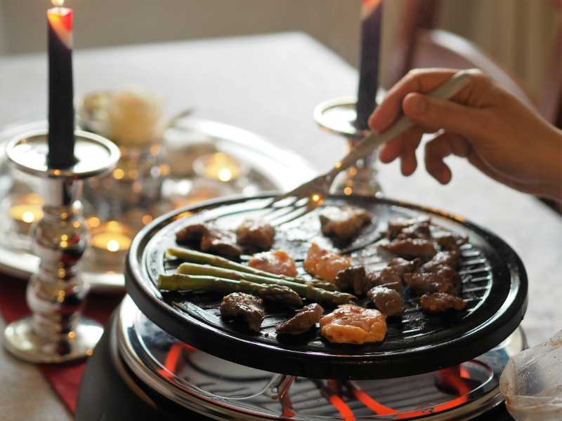 bilde av et sosialt måltid, raclette med kjøtt og asparges